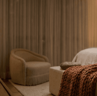Quarto aconchegante com poltrona e manta terracota - Aracá Interiores
